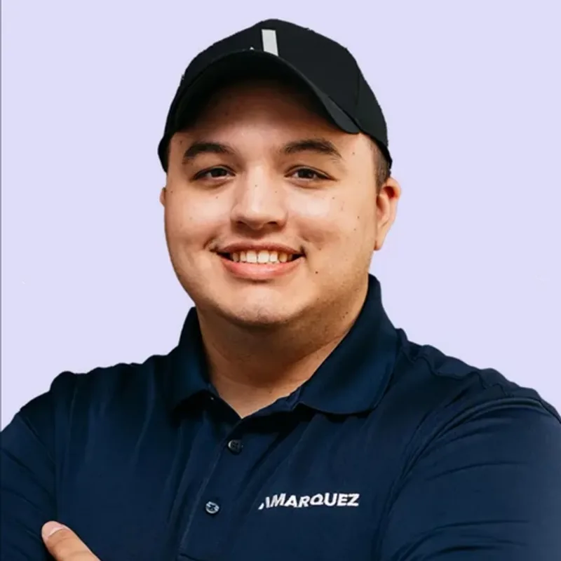 Aaron Marquez, CEO of AMARQUEZ, smiling, in a navy AMARQUEZ polo and cap.